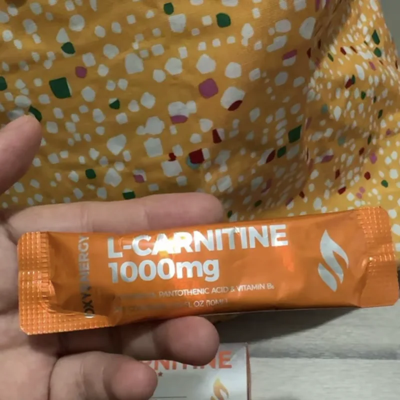 Buyer's photo — a single L-Carnitine 1000mg sachet held in the hand, the box behind it