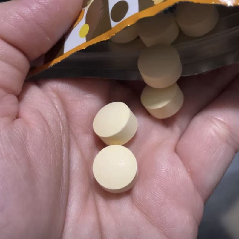 Buyer’s photo of two chewable tablets in the palm of a hand, tipped from the pouch